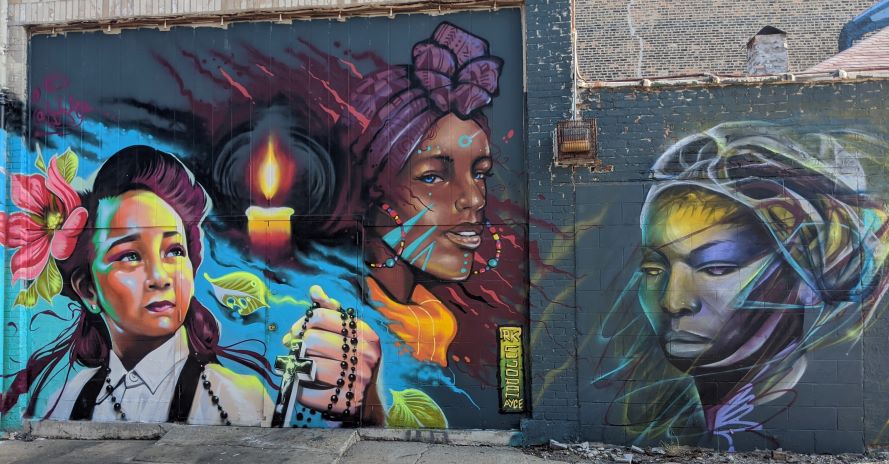 Rainbow runs through a mural of Afro-latinx individuals celebrating their own expression.
