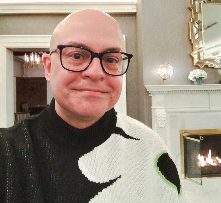 Man in black and white sweater with glasses.