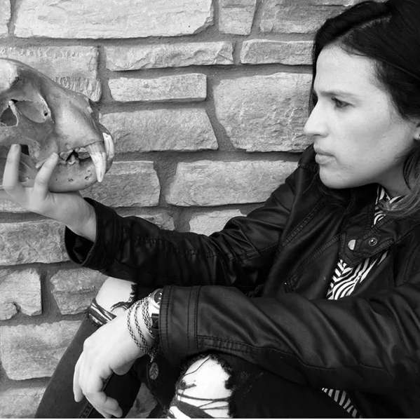 Woman in black jacket holding an animal's skull.